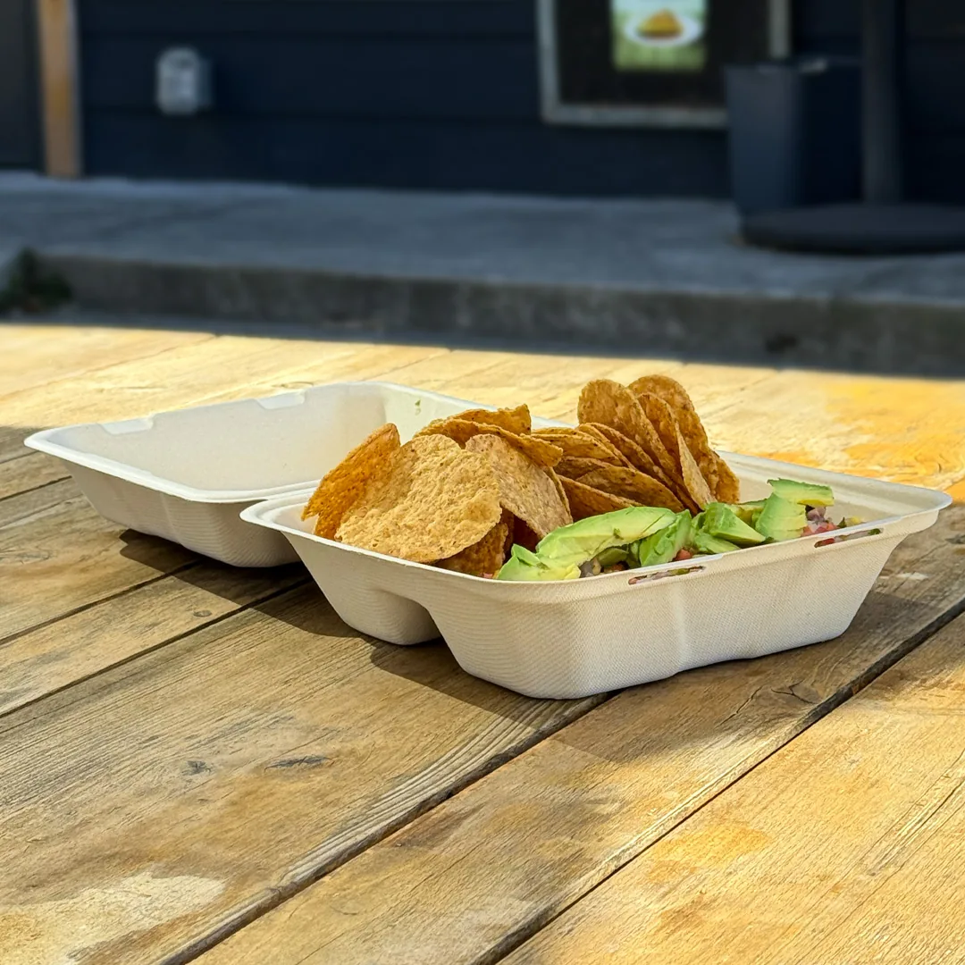 A ceviche with tortilla chips on an outdoor wooden table outside the shop